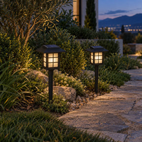 Duas luminárias solares Kaori com luz quente ao lado de um caminho de jardim
