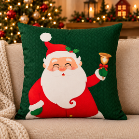 Detalhe da capa de almofada Noelina Celebração verde, com estampa de Papai Noel e ornamento dourado.